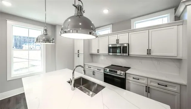 a kitchen with stainless steel appliances a stove a sink and microwave