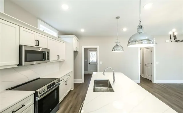 a kitchen with stainless steel appliances a stove a sink a microwave a refrigerator and cabinets