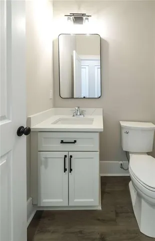 a bathroom with a toilet sink vanity and mirror