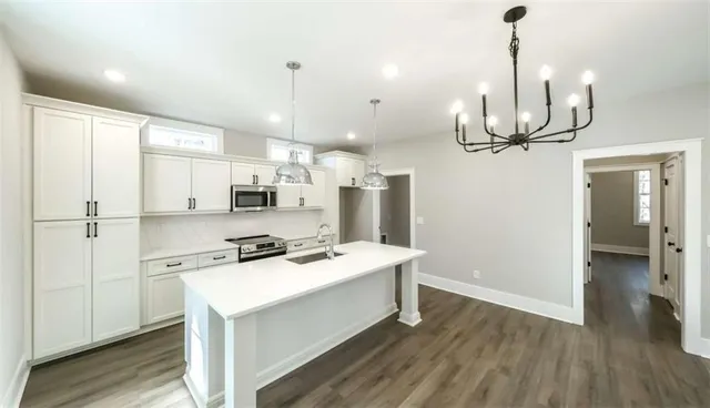 a kitchen with stainless steel appliances granite countertop a sink a stove a refrigerator and island with wooden floor