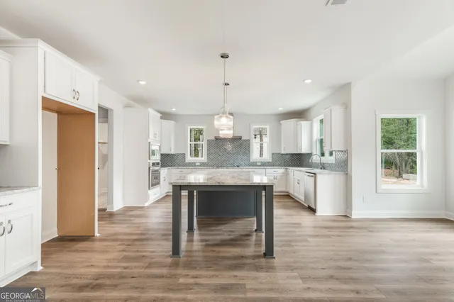 a kitchen with stainless steel appliances granite countertop a stove a sink a window and chairs