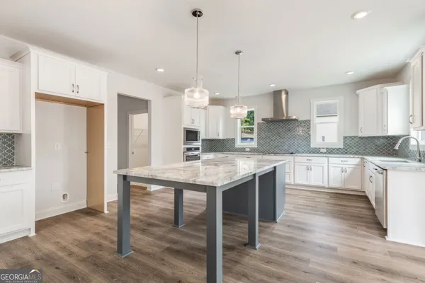 a kitchen with stainless steel appliances granite countertop wooden floor window and cabinets