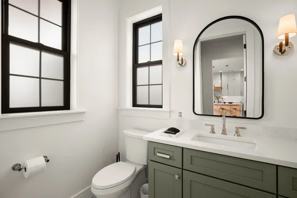 a bathroom with a toilet a sink a mirror and a window