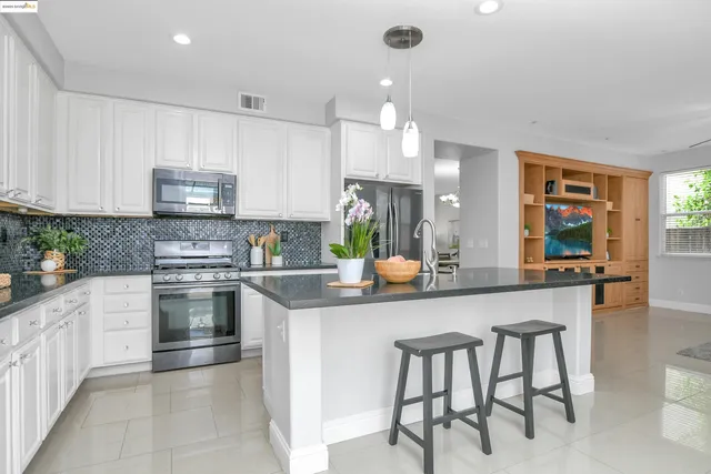 a kitchen with stainless steel appliances granite countertop a table chairs sink and cabinets