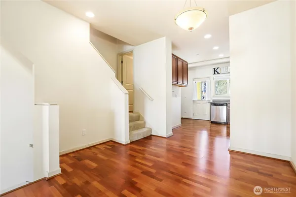 a view of an empty room with wooden floor and stairs