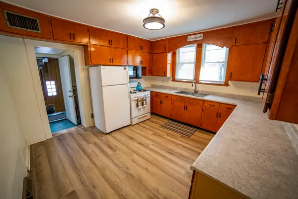 a view of a kitchen with fridge and wooden floor