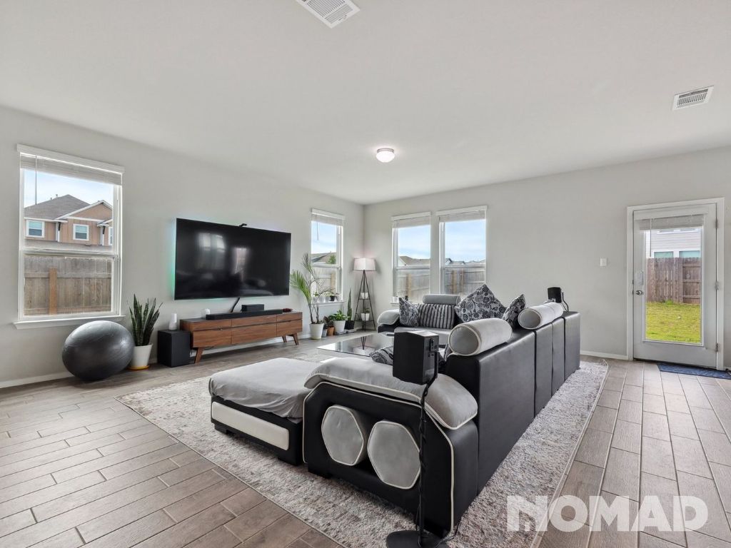 101 Crescent Street Georgetown, TX 78626 - Photo 6 of 28 a living room with furniture a flat screen tv and a floor to ceiling window