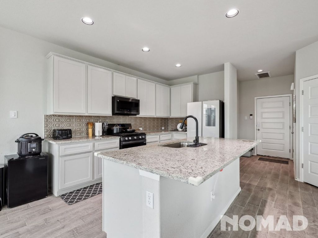 101 Crescent Street Georgetown, TX 78626 - Photo 8 of 28 a kitchen with granite countertop a refrigerator a sink a stove a microwave and island