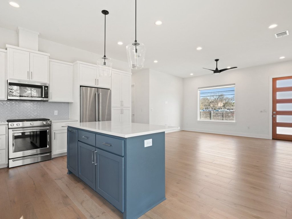 709 West St Elmo Road, Unit 2 Austin, TX 78745 - Photo 26 of 26 Kitchen featuring two tone cabinetry, stainless steel appliances, pendant lighting, open floor plan, and light wood-style floors