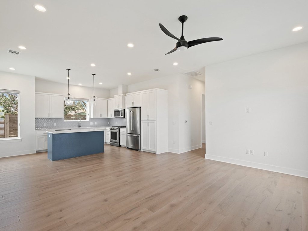 709 West St Elmo Road, Unit 2 Austin, TX 78745 - Photo 25 of 26 Dual tone kitchen with decorative light fixtures, dual tone cabinetry, open floor plan, a ceiling fan, and stainless steel appliances