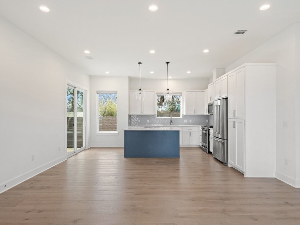 709 West St Elmo Road, Unit 2 Austin, TX 78745 - Photo 9 of 26 Kitchen with decorative light fixtures, light countertops, a kitchen island, stainless steel appliances, and dark wood finished floors
