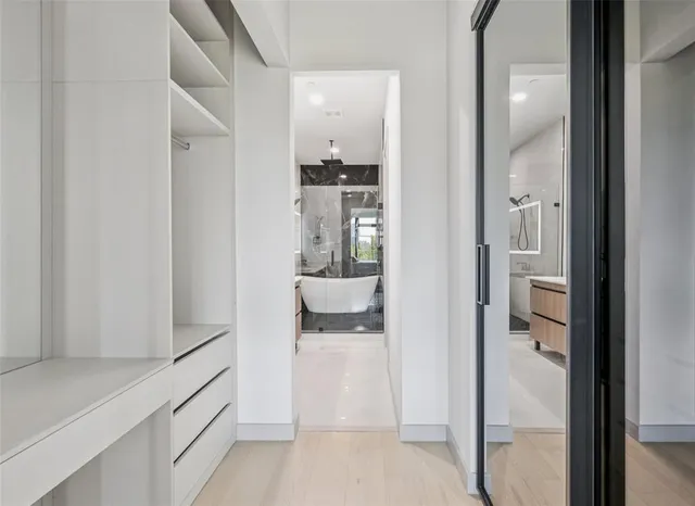 a view of a hallway with wooden floor and a bathroom