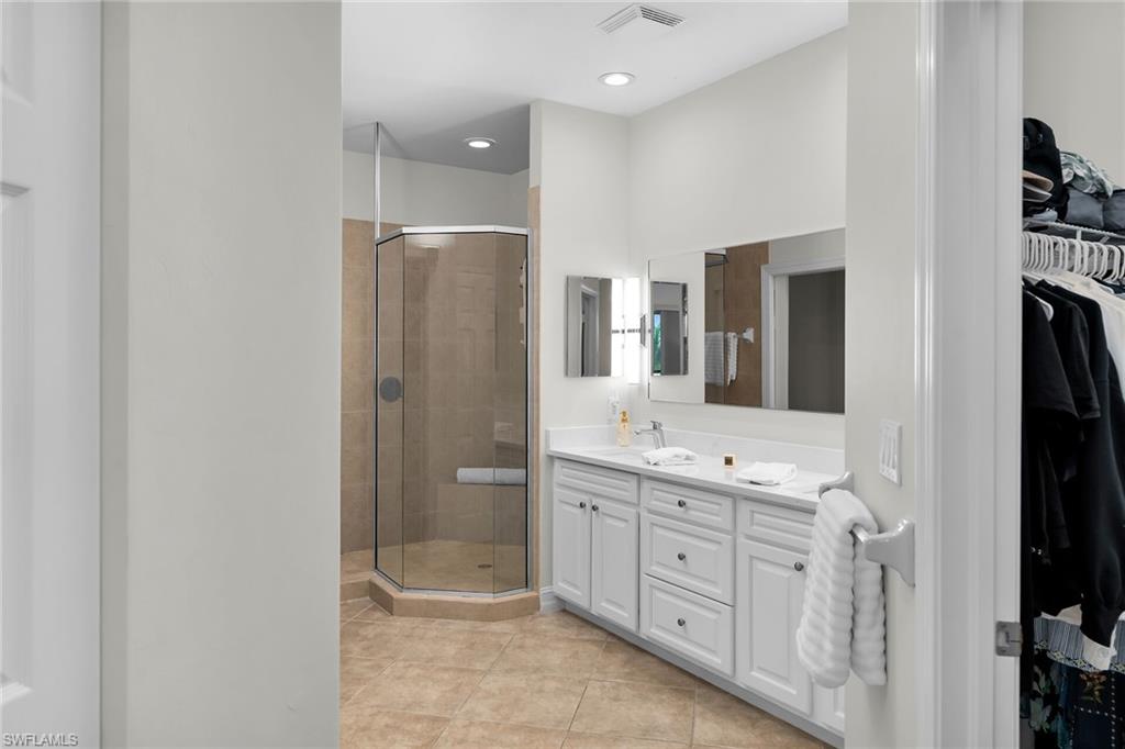 1286 Rialto Way, Unit 9202 Naples, FL 34114 - Photo 19 of 49 Primary bathroom with stall shower, double vanity, updated cabinetry, new white quartz countertops, tile flooring, and recessed lighting.