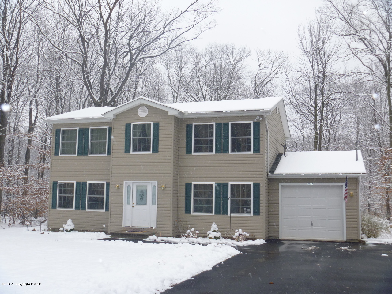 a front view of a house with a yard covered in snow
