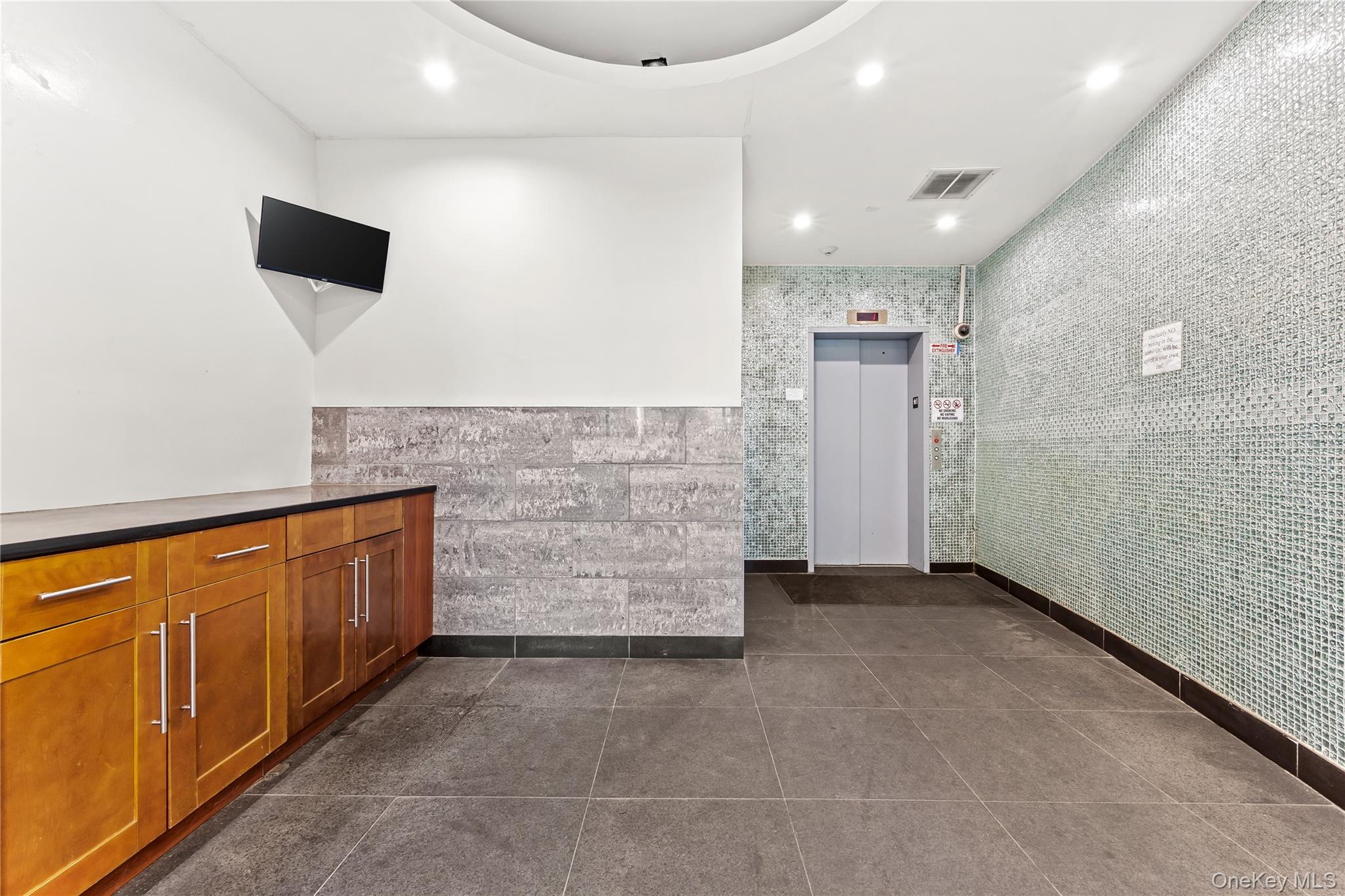 95-08 65th Road, Unit 3C Queens, NY 11374 - Photo 15 of 19 Reception area with tile walls and recessed lighting