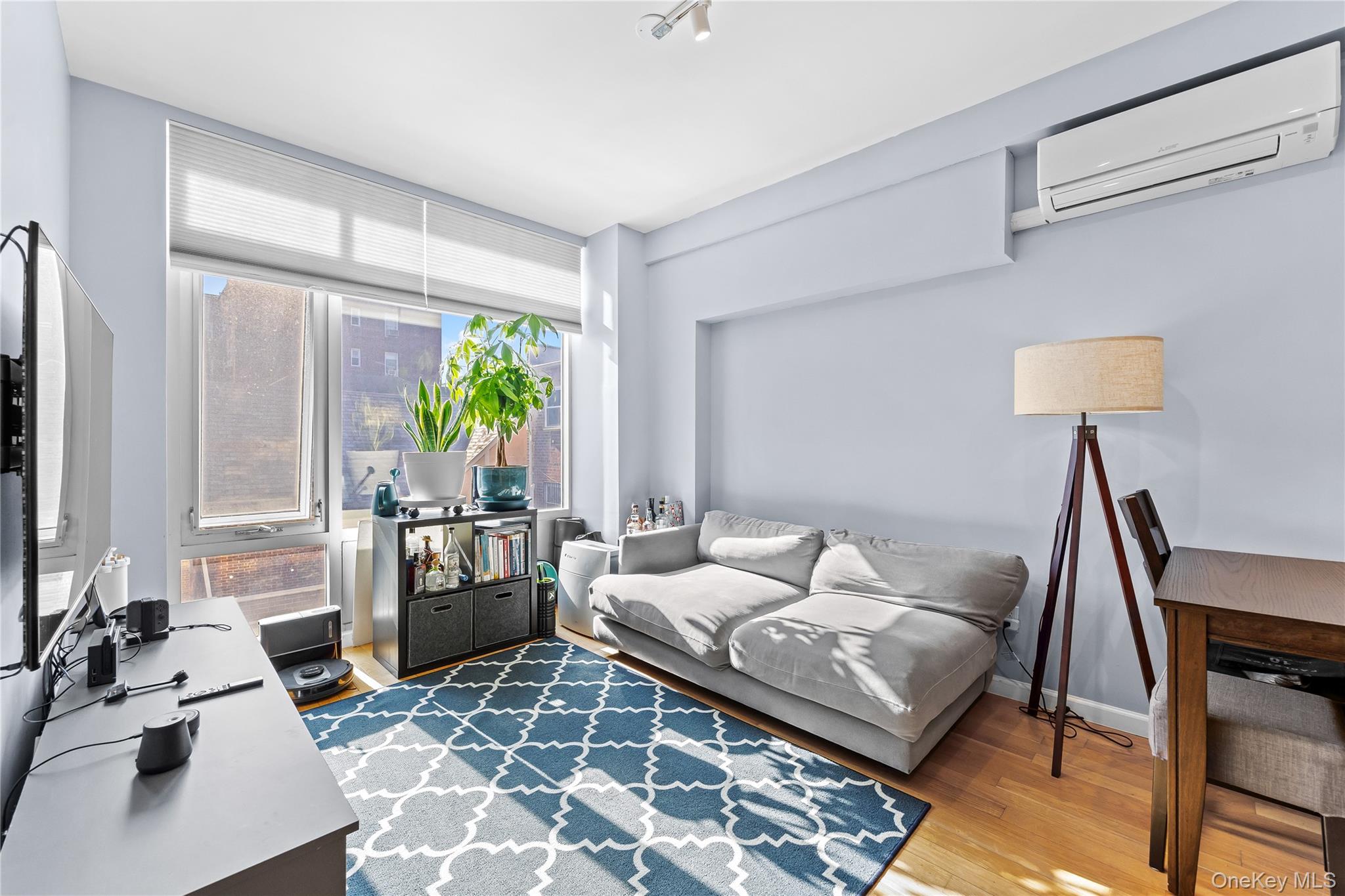 95-08 65th Road, Unit 3C Queens, NY 11374 - Photo 3 of 19 Living area with a wall mounted air conditioner, wood finished floors, and a desk