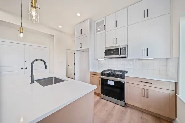 a kitchen with a sink appliances wooden floor and a window