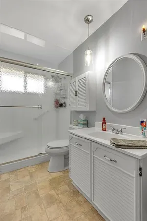 a bathroom with a toilet a sink a mirror and a shower
