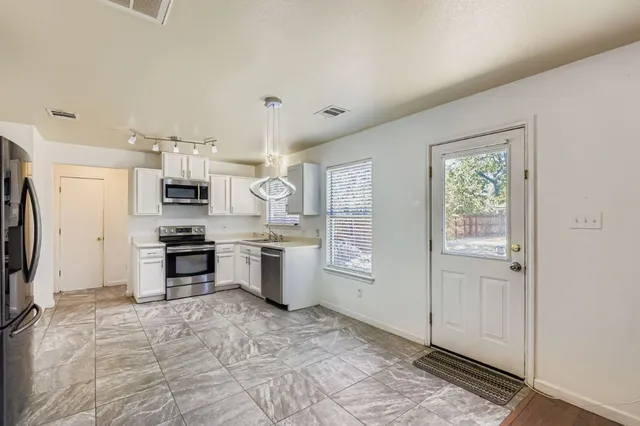 a large white kitchen with granite countertop a stove a sink and a refrigerator