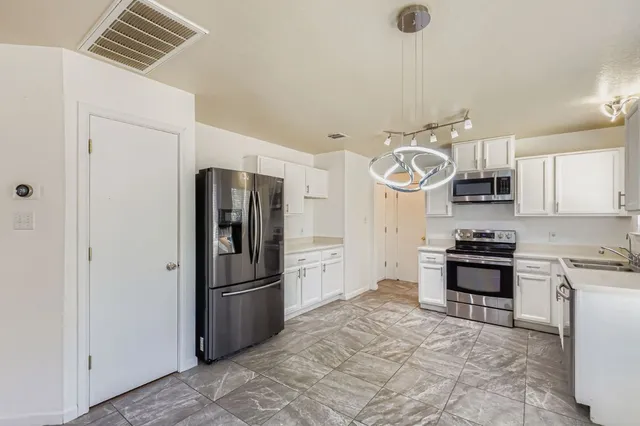 a kitchen with stainless steel appliances granite countertop a refrigerator a stove and a sink
