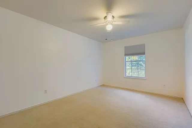 an empty room with a chandelier fan and windows