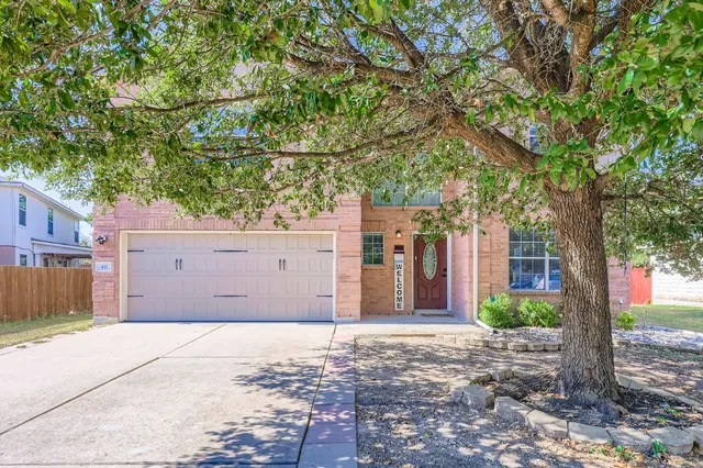 a front view of a house with a tree
