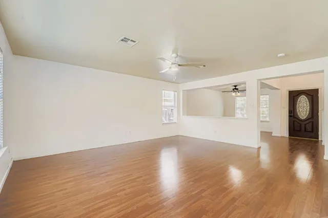 a view of an empty room with window and wooden floor
