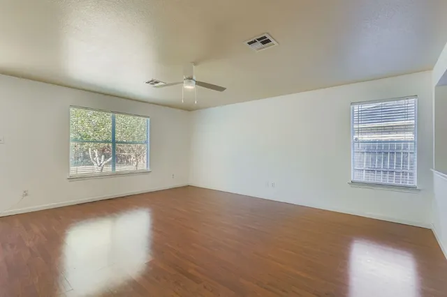 a view of an empty room with wooden floor and a window