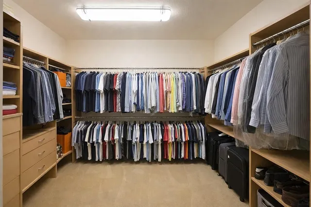 a view of walk in closet with clothes and shoes