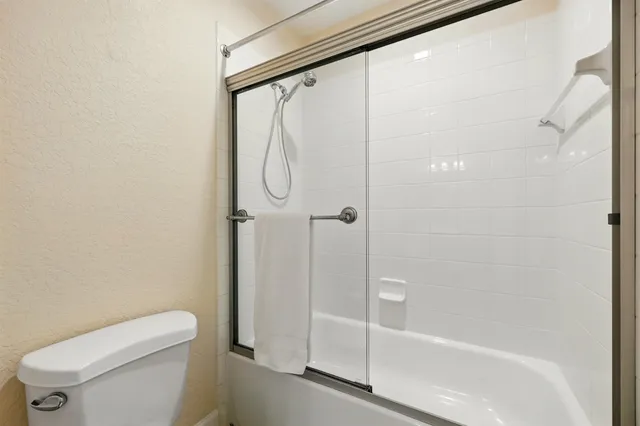 a bathroom with a shower a toilet and a glass window