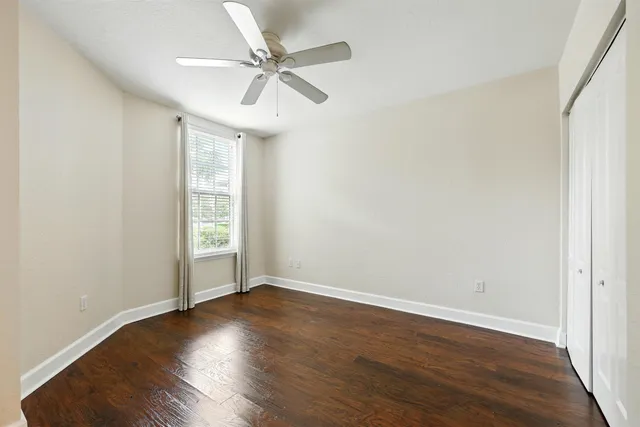 an empty room with wooden floor fan and windows