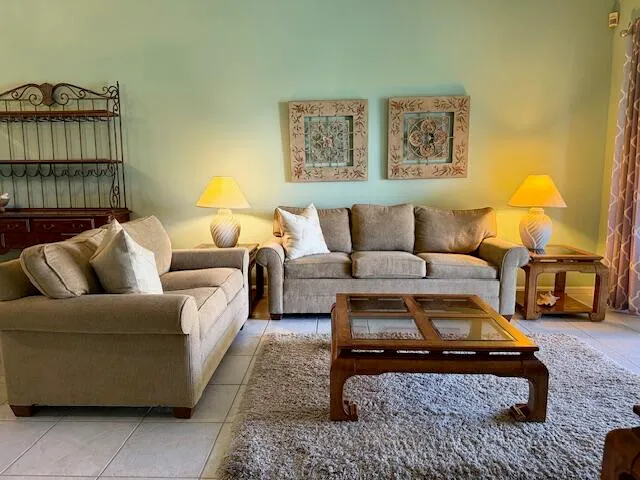 a living room with furniture a rug and wall paintings