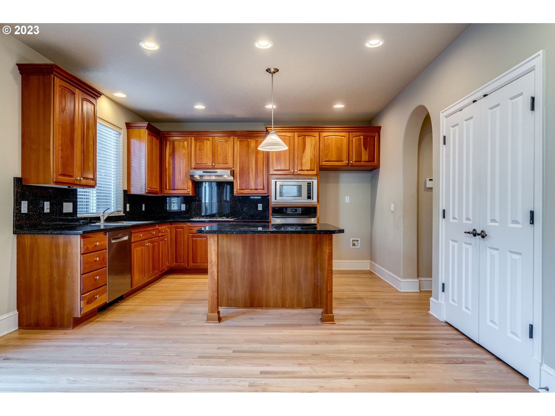 12581 Northwest Forest Spring Lane Portland, OR 97229 - Photo 16 of 48 a kitchen with stainless steel appliances granite countertop wooden cabinets a refrigerator a stove a sink and dishwasher with wooden floor