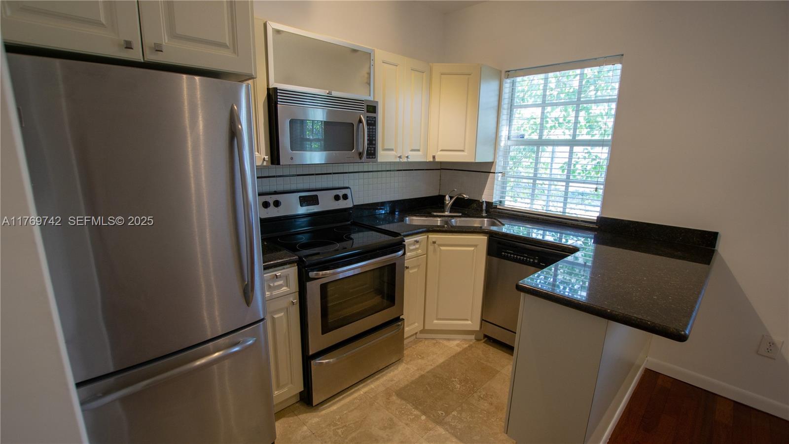 577 Northeast 62nd Street, Unit 2 Miami, FL 33138 - Photo 17 of 21 a kitchen with granite countertop a refrigerator stove and microwave