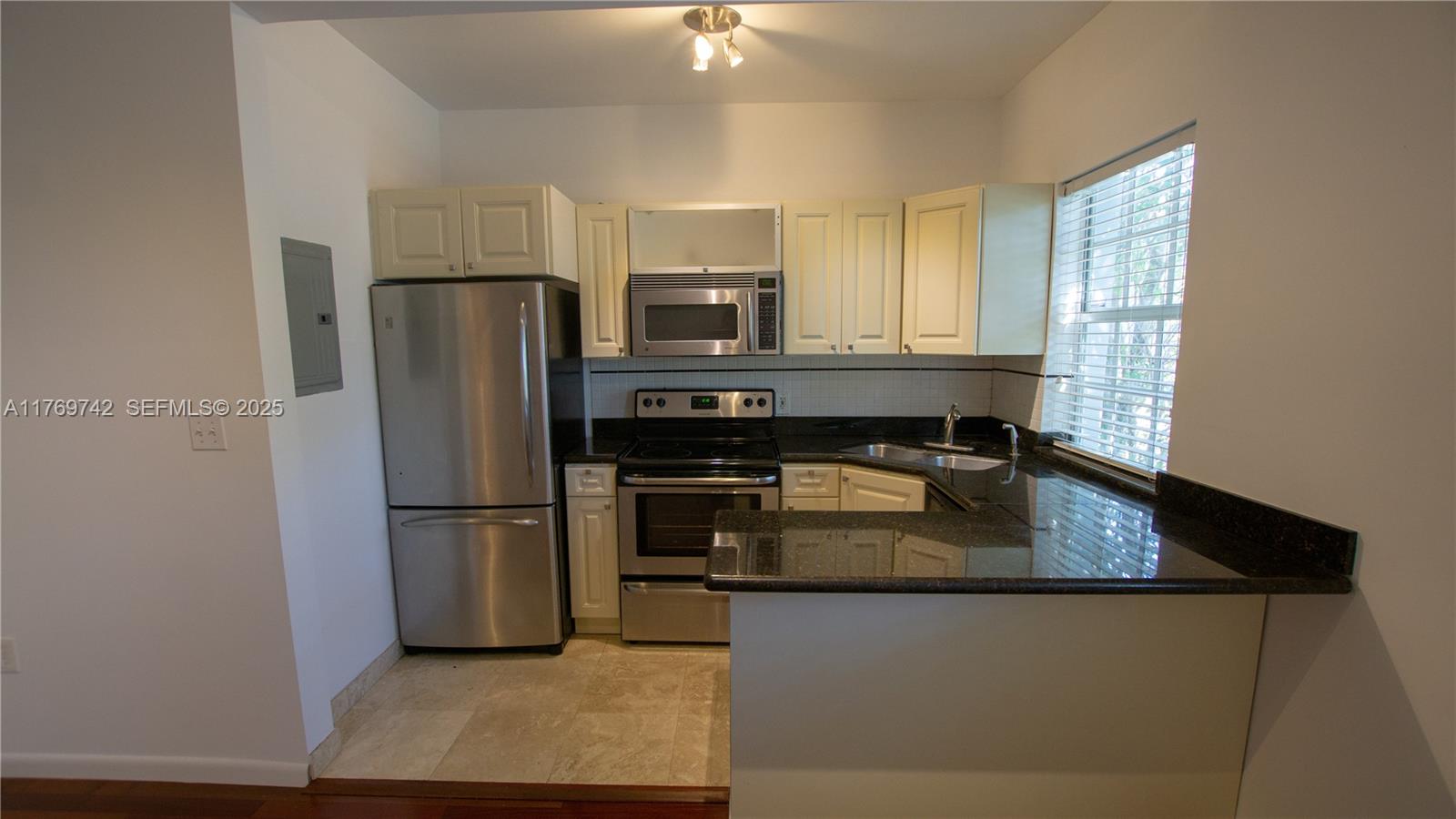 577 Northeast 62nd Street, Unit 2 Miami, FL 33138 - Photo 18 of 21 a kitchen with kitchen island a counter top space appliances and a refrigerator