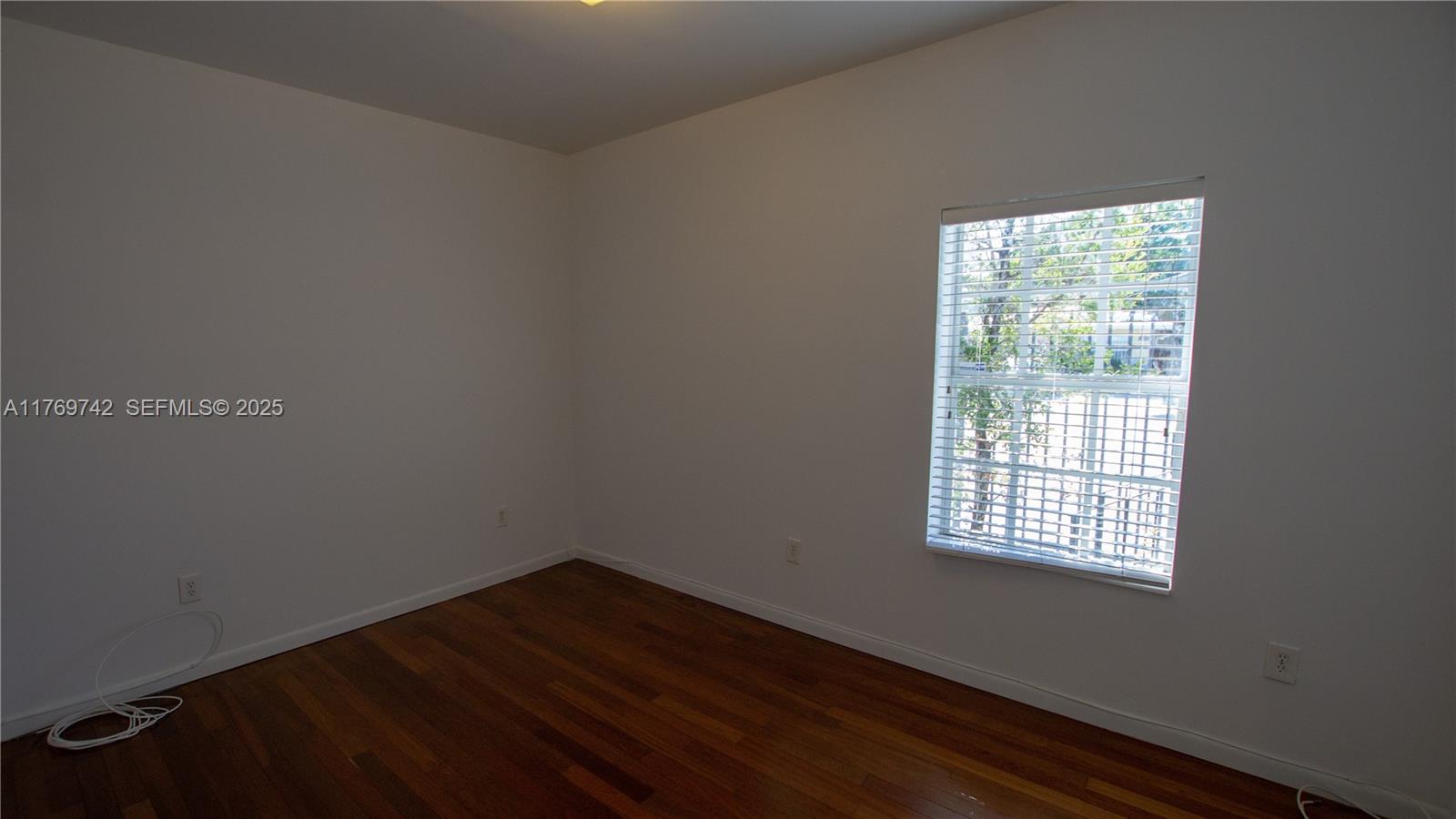 577 Northeast 62nd Street, Unit 2 Miami, FL 33138 - Photo 7 of 21 a view of an empty room with wooden floor and a window