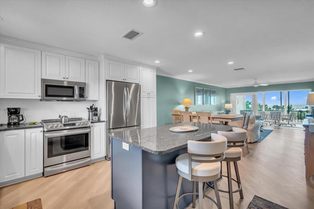 757 Beach Road, Unit 310 Sarasota, FL 34242 - Photo 8 of 31 a kitchen with a dining table chairs stove microwave and cabinets