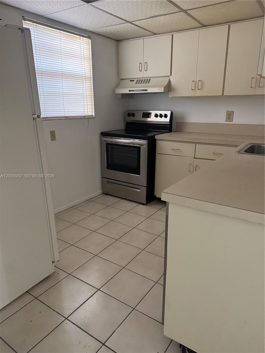 7747 Southwest 86th Street, Unit D105 Miami, FL 33143 - Photo 6 of 14 a kitchen with stainless steel appliances a stove a microwave and a refrigerator