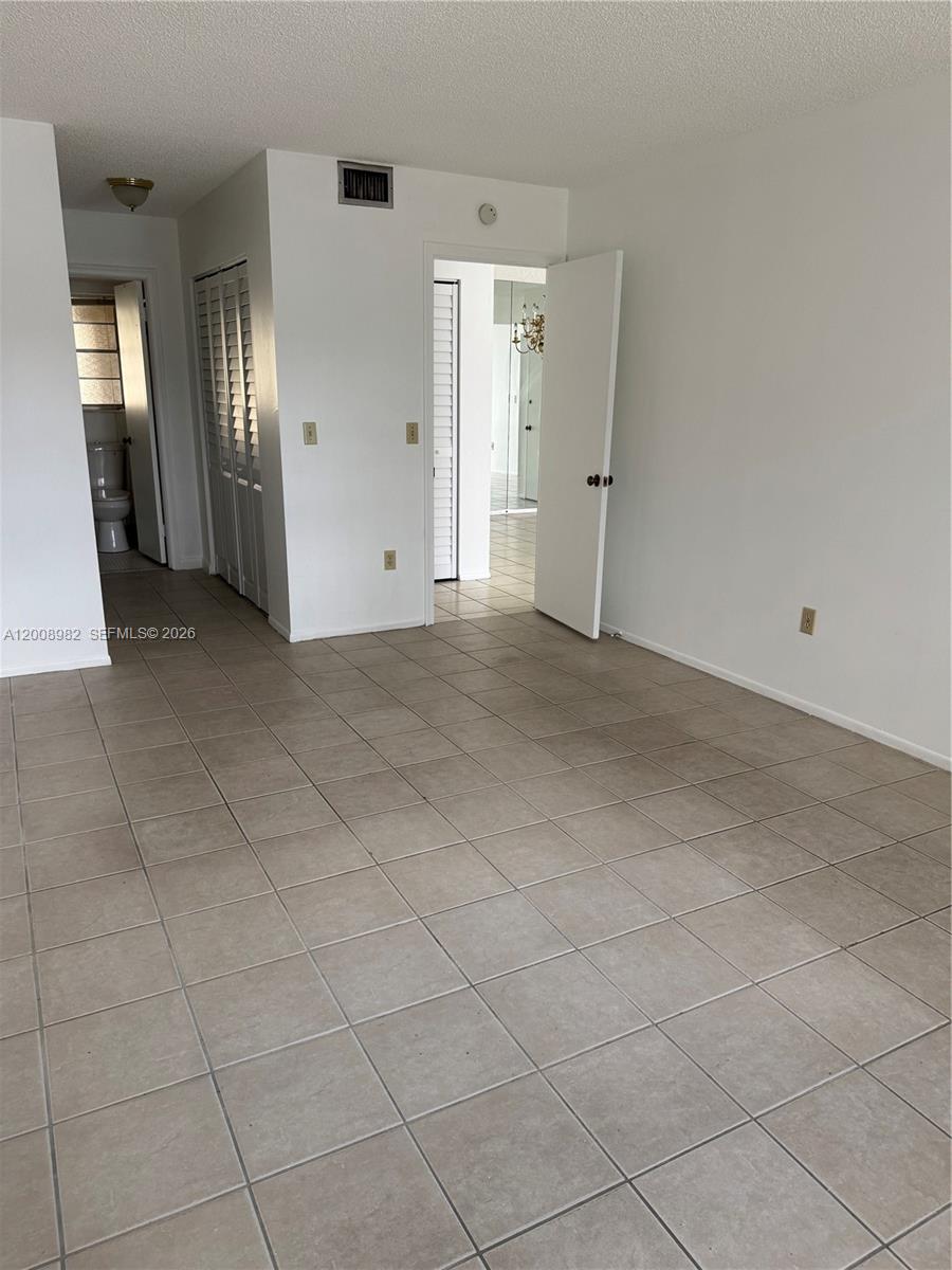 7747 Southwest 86th Street, Unit D105 Miami, FL 33143 - Photo 8 of 14 an empty room with staircase and mirror