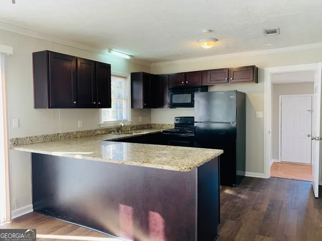 a kitchen with stainless steel appliances granite countertop a refrigerator a sink a stove a microwave and wooden cabinets