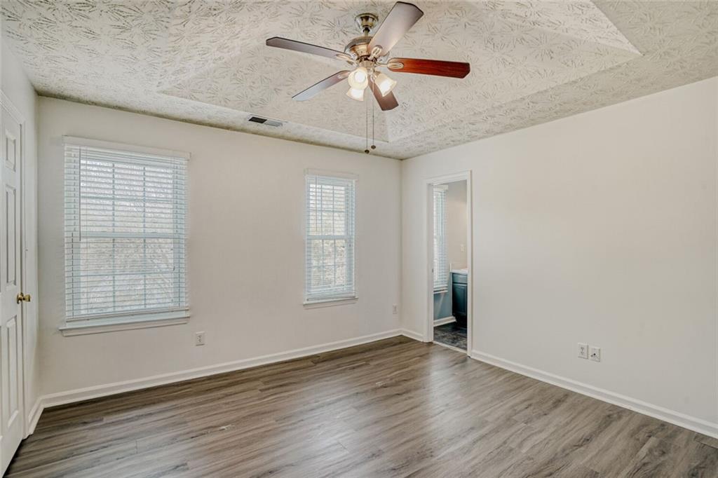 4120 Spring Cove Drive Duluth, GA 30097 - Photo 11 of 24 an empty room with wooden floor chandelier fan and windows