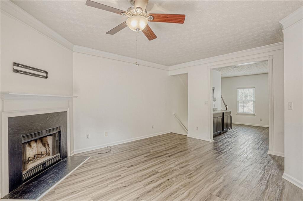 4120 Spring Cove Drive Duluth, GA 30097 - Photo 4 of 24 an empty room with wooden floor a ceiling fan a fireplace and windows