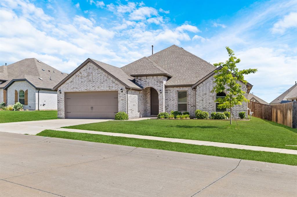 915 Timber Ridge Drive Justin, TX 76247 - Photo 4 of 39 Light-colored brick exterior featuring a prominent front-facing garage with a tan door