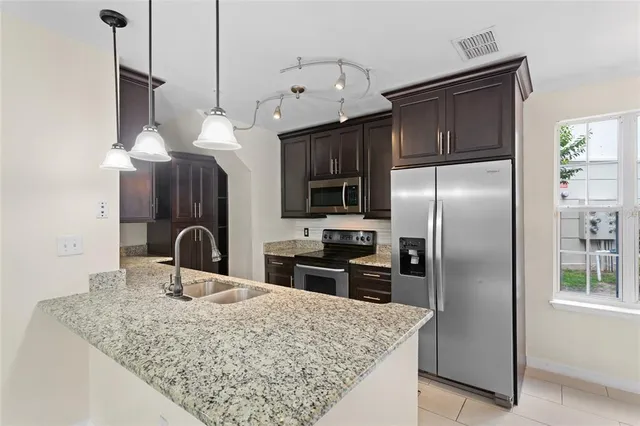 a kitchen with stainless steel appliances granite countertop a refrigerator a sink and a stove