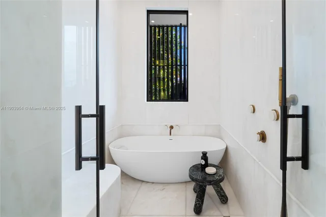 a view of a brick house with a small yard plants and a large tree