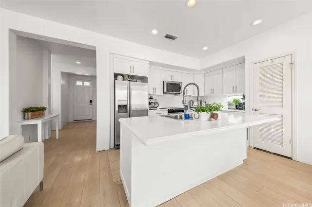 a view of living room kitchen with stainless steel appliances furniture refrigerator and cabinets