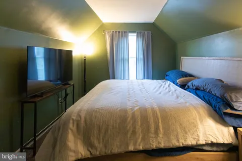 a bedroom with a bed and a flat tv screen on dresser