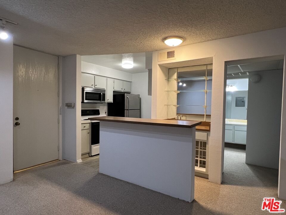 1115 Raintree Circle Culver City, CA 90230 - Photo 11 of 32 a open kitchen with stainless steel appliances kitchen island granite countertop a refrigerator and a sink