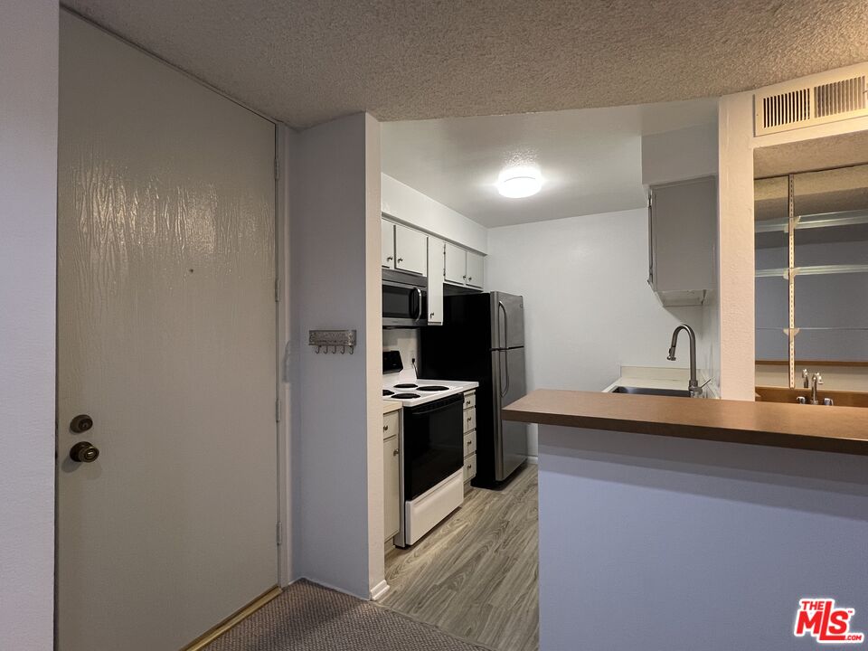 1115 Raintree Circle Culver City, CA 90230 - Photo 12 of 32 a kitchen with stainless steel appliances granite countertop a sink and a refrigerator
