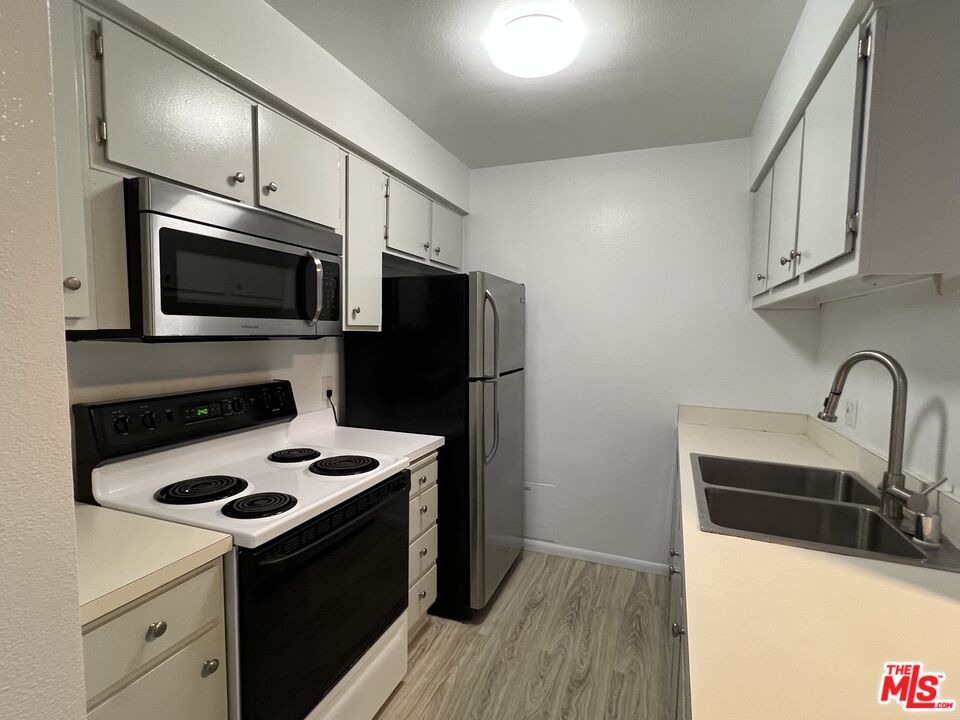 1115 Raintree Circle Culver City, CA 90230 - Photo 9 of 32 a kitchen with stainless steel appliances a sink a stove a microwave and wooden cabinets